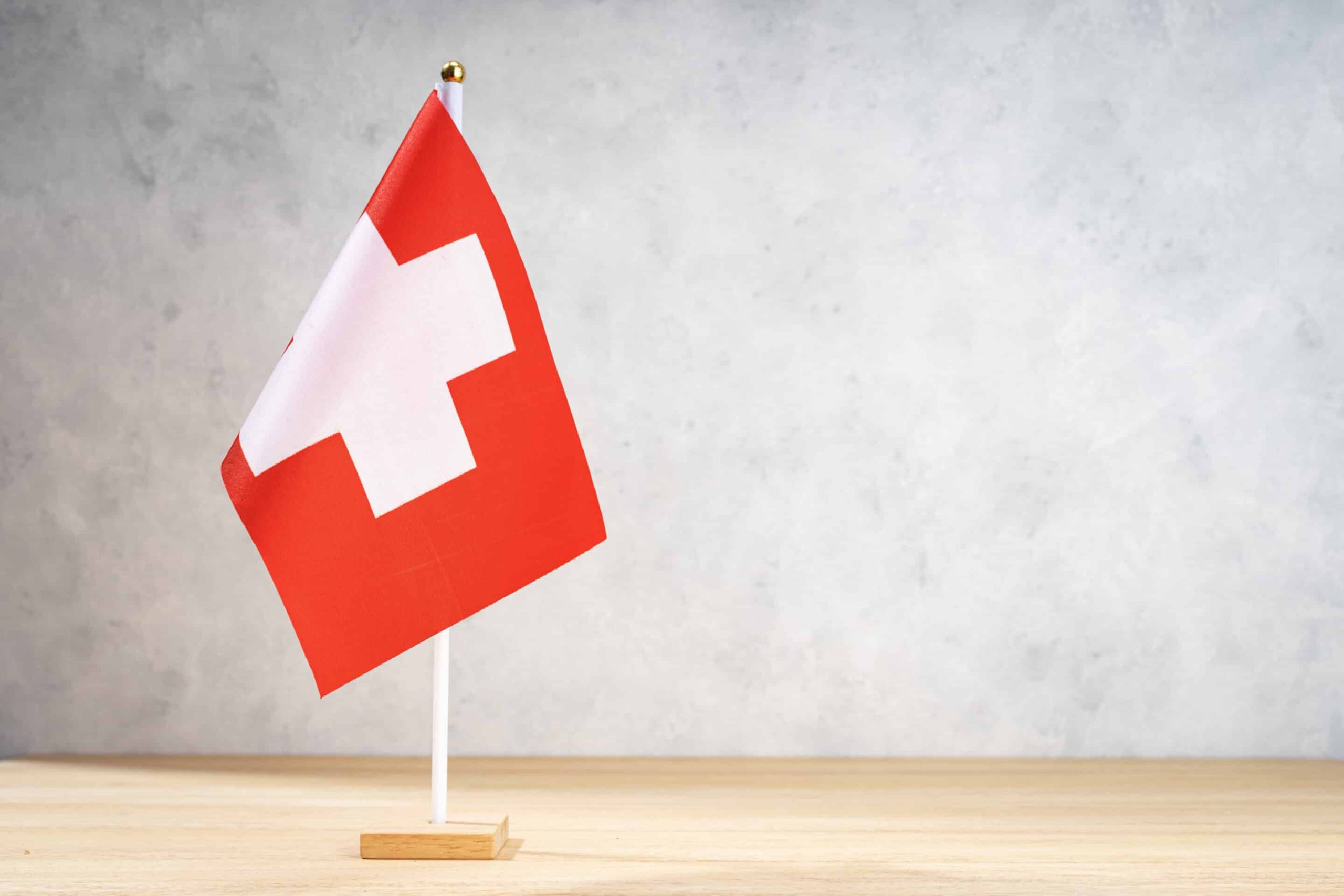 Switzerland table flag on white textured wall. Copy space for te